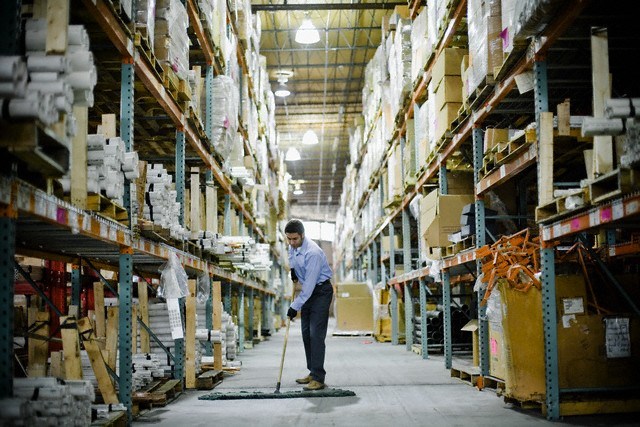 Warehouse Worker Sweeping --- Image by © Sean Justice/Corbis